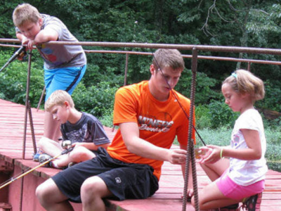 A Counselor and campers on the bridge at Camp 
Carew